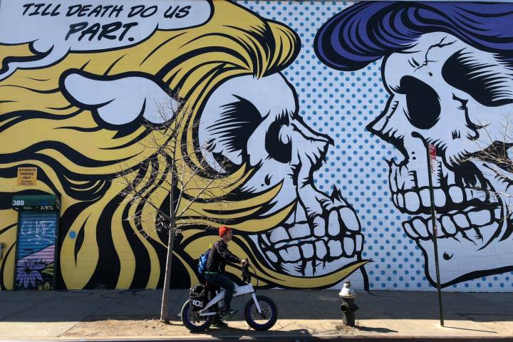 big mural of skulls with ebike rider in front of it