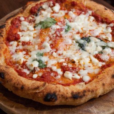 A cheese pizza with fresh basil on a wooden board.