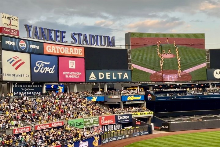 Crowd at Yankee Stadium with scoreboard and large screens visible.