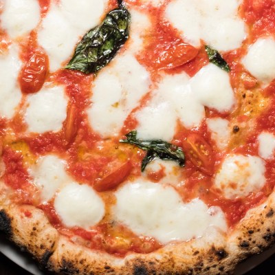 Neapolitan pizza with mozzarella, tomatoes, and basil on a white plate.