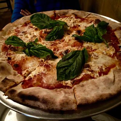 Pizza with fresh basil leaves on a silver tray, showing melted cheese and tomato sauce.