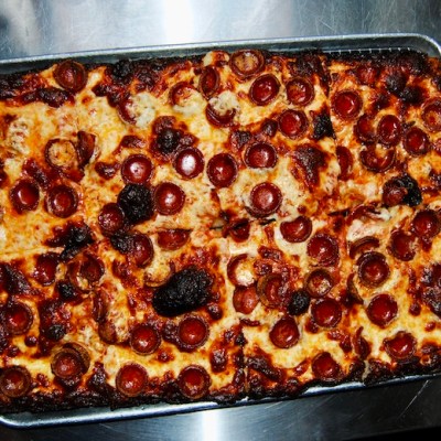 Rectangular pepperoni pizza with crispy edges on a metal tray.