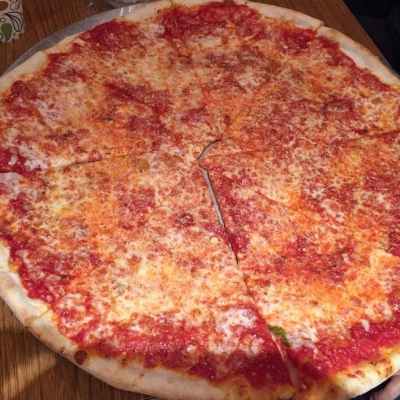 Large cheese pizza with tomato sauce on a wooden table.