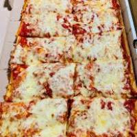 Rectangular pizza with melted cheese cut into square slices in a box.