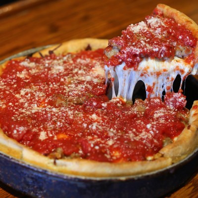Deep dish pizza with cheese pull and tomato sauce topping.