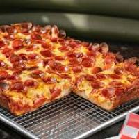 Rectangular pepperoni pizza on wire rack over a baking tray.