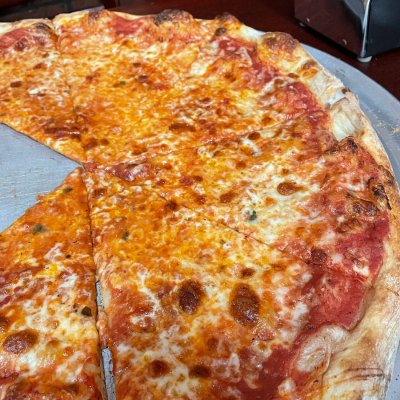 Cheese pizza on metal tray with crispy crust and hearty tomato sauce.