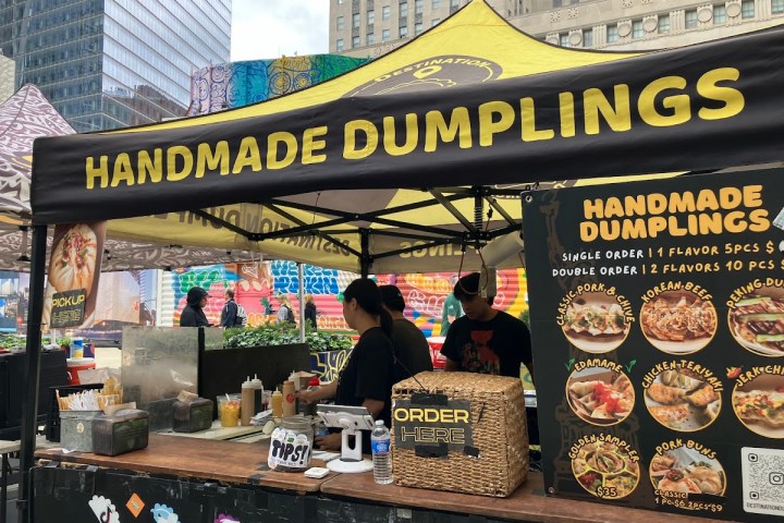 Outdoor food stall selling handmade dumplings at a city market.