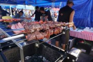 Skewers of grilled meat on a barbeque at an outdoor market.