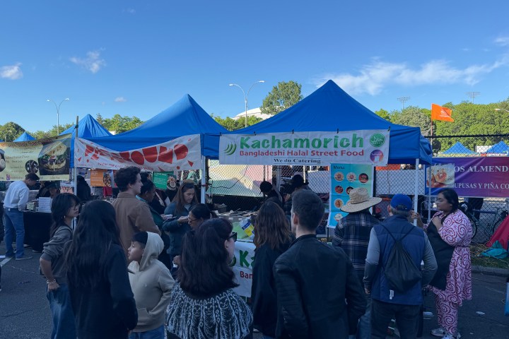 Outdoor food festival with a crowd at Bangladeshi street food stall under blue tents.