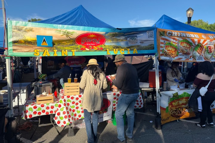 People at a food stall with Saint Lucia sign at an outdoor market.