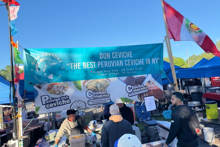 Outdoor market stall selling Peruvian ceviche with people and banners.