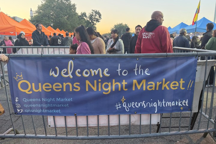 People gather at Queens Night Market entrance with welcome banner.